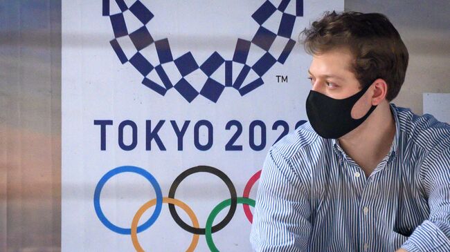 A man wearing a facemask, amid concerns over the spread of the COVID-19 coronavirus, sits at a bus stop in front of a Tokyo 2020 Olympics advertisement in Bangkok on March 16, 2020. (Photo by Mladen ANTONOV / AFP)