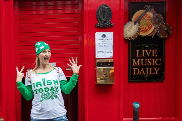 Женщина позирует возле закрытого паба в Дублине в День святого Патрика