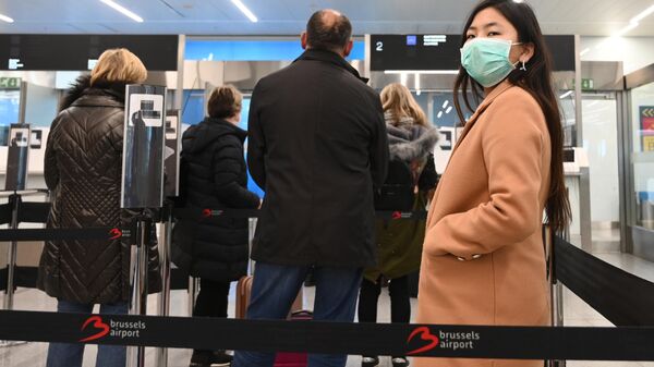 Пассажиры в медицинских масках в зоне регистрации в аэропорту Брюсселя