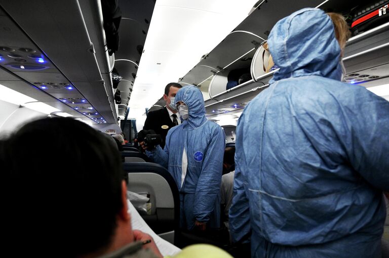 Сотрудники Роспотребнадзора измеряют температуру пассажиров на борту самолета в аэропорту Шереметьево Сотрудники Роспотребнадзора измеряют температуру пассажиров на борту самолета в аэропорту Шереметьево