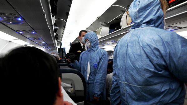 Сотрудники Роспотребнадзора измеряют температуру пассажиров на борту самолета в аэропорту Шереметьево