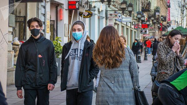 Прохожие в медицинских масках на улице Тбилиси