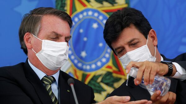 Президент Бразилии Жаир Болсонару и министр здравоохранения Луис Энрике Мандетта дезинфицируют руки во время пресс-конференции