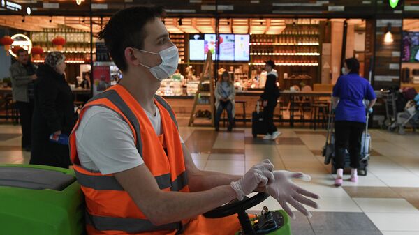 Сотрудник клининговой службы в медицинской маске в аэропорту Толмачево в Новосибирске