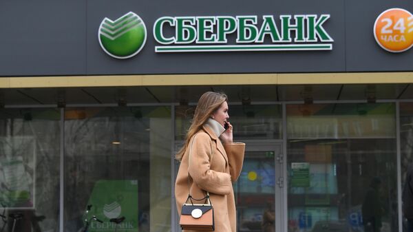 Девушка проходит мимо отделения ПАО Сбербанк на одной из улиц в Москве