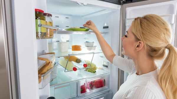 Девушка достает продукты из холодильника