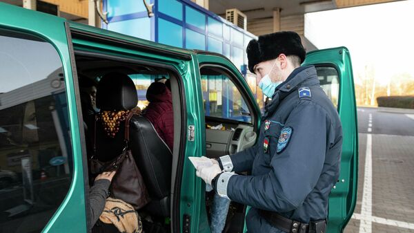 Сотрудник венгерской полиции проверяет документы украинских рабочих, покидающих Венгрию на пограничном пункте в городе Захонь, северо-восточная Венгрия