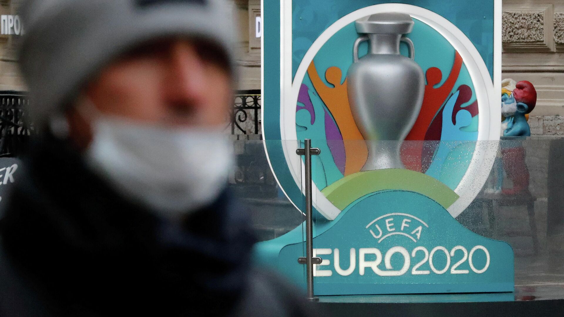 Человек в маске на фоне логотипа Евро-2020 - РИА Новости, 1920, 25.12.2020