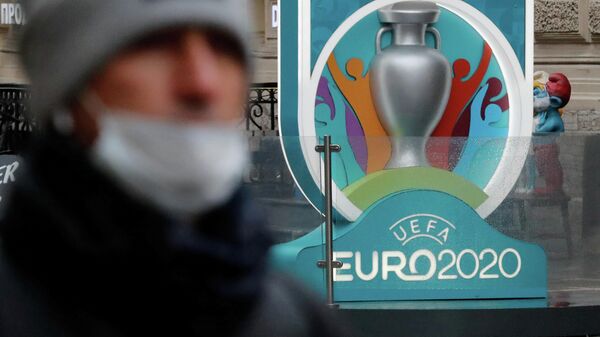 Человек в маске на фоне логотипа Евро-2020
