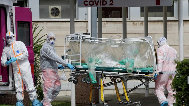 Медицинские работники несут пациента, доставленного в больницу Columbus Covid 2 в Риме
