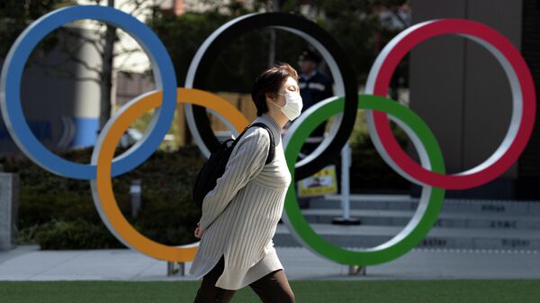 A woman wearing a protective face mask, following an outbreak of the coronavirus disease (COVID-19), walks past the Olympic rings in front of the Japan Olympics Museum in Tokyo, Japan March 13, 2020. REUTERS/Athit Perawongmetha