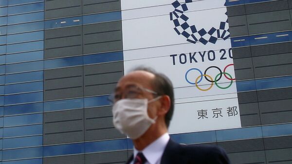 FILE PHOTO : A man, wearing a protective mask following an outbreak of the coronavirus disease (COVID-19) is pictured in front of a banner for the upcoming Tokyo 2020 Olympics in Tokyo, Japan, March 12, 2020. REUTERS/Edgard Garrido/File Photo