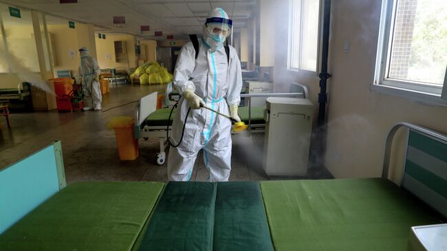 Работник в защитном костюме дезинфицирует больницу № 7 города Ухань