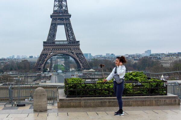 Туристка фотографируется на безлюдной площади Трокадеро у Эйфелевой башни в Париже