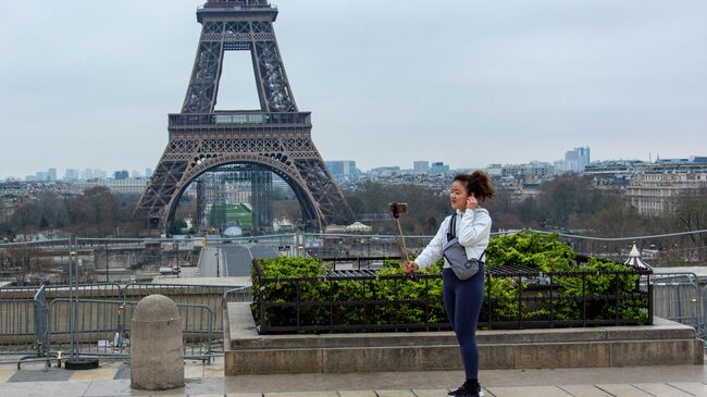 Туристка фотографируется на безлюдной площади Трокадеро у Эйфелевой башни в Париже