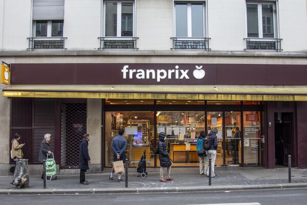 Люди стоят в очереди возле продуктового магазина в Париже