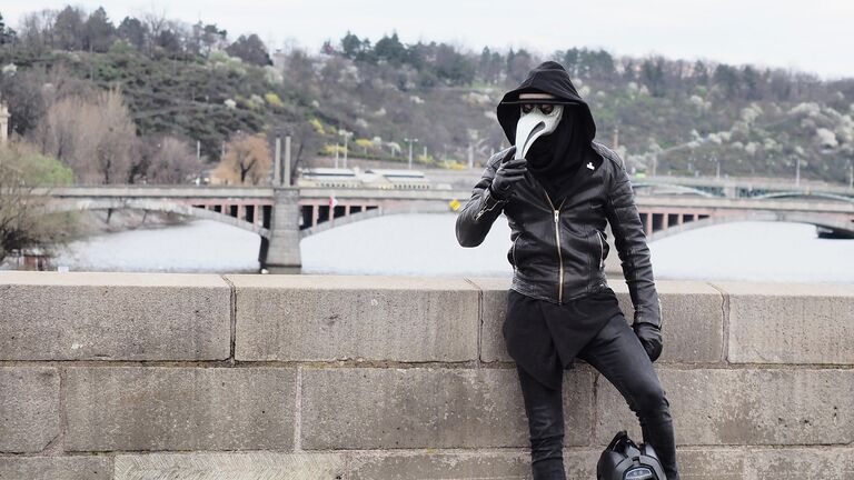 Мужчина в маске на опустевшей в связи с угрозой заражения вирусом COVID-19 улице Праги