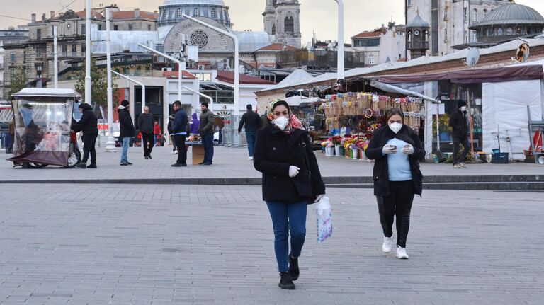 Прохожие в медицинских масках на одной из улиц в Стамбуле