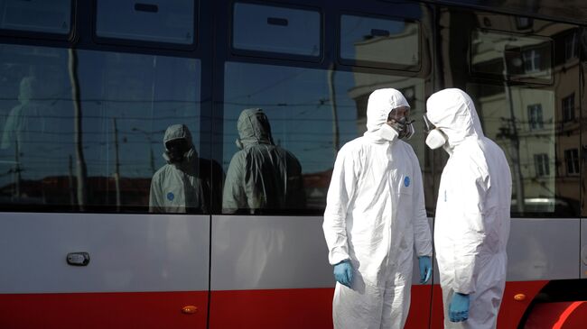Рабочие в защитных костюмах готовятся во время дезинфекции трамваев в Праге