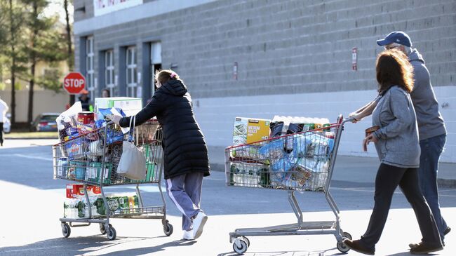 Покупатели выходят из магазина в Мелвилле, штат Нью-Йорк