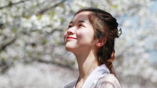 Девушка наблюдает за цветением сакуры в Нанкине