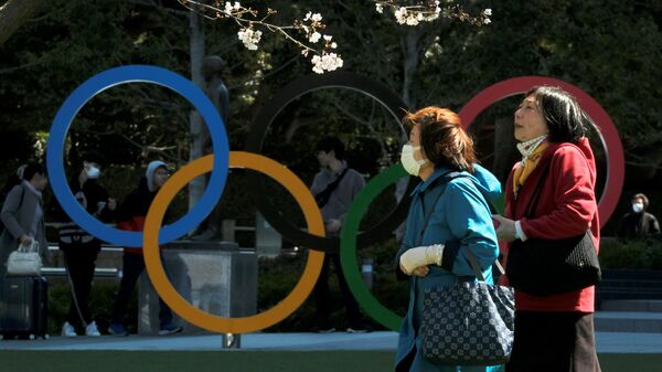 Pedestrians walk past an installation of the Olympic rings in Tokyo on March 24, 2020. - The International Olympic Committee came under pressure to speed up its decision about postponing the Tokyo Games on March 24 as athletes criticised the four-week deadline and the United States joined calls to delay the competition. (Photo by Kazuhiro NOGI / AFP)