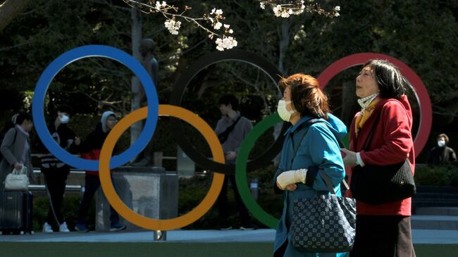 Pedestrians walk past an installation of the Olympic rings in Tokyo on March 24, 2020. - The International Olympic Committee came under pressure to speed up its decision about postponing the Tokyo Games on March 24 as athletes criticised the four-week deadline and the United States joined calls to delay the competition. (Photo by Kazuhiro NOGI / AFP)