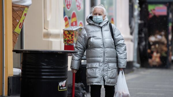 Женщина в медицинской маске идет по улице Симферополя