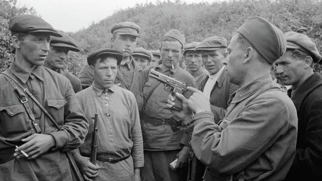 Командир партизанского отряда знакомит бойцов с оружием. Смоленская область, Россия