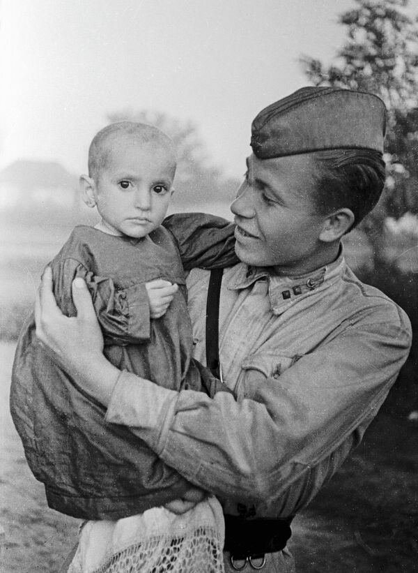 Советский офицер держит на руках спасённую им девочку из деревни Эльхотово