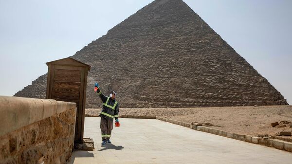 Рабочий во время дезинфекции комплекса пирамид в Гизе