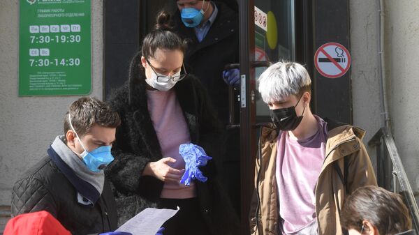 Молодые люди в защитных масках у входа в медицинскую лабораторию Гемотест в Москве