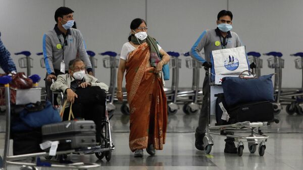Персонал аэропорта сопровождает пожилых людей после вспышки коронавируса в Нью-Дели, Индия