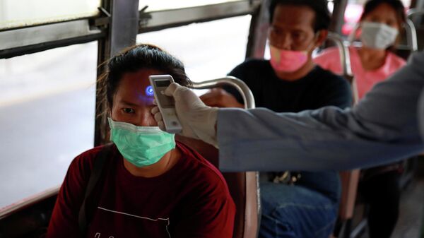 Проверка температуры тела у пассажира на КПП в Бангкоке в связи со вспышкой коронавируса в Таиланде