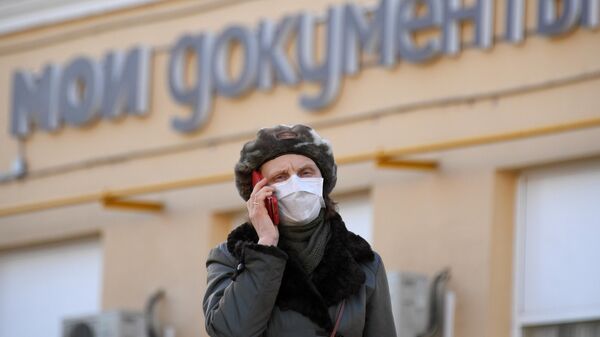 Женщина в медицинской маске около одного из центров Мои документы в Москве
