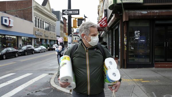 Мужчина идет из магазина в защитной маске во время вспышки COVID-19, Нью-Йорк