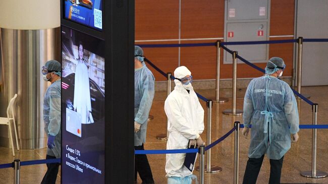 Медики в защитных костюмах в зоне прилета в аэропорту Шереметьево