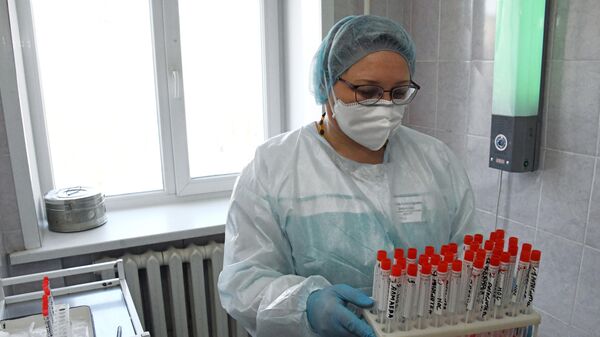 Врач держит в руках пробирки с образцами биоматериалов для тестирования на коронавирус