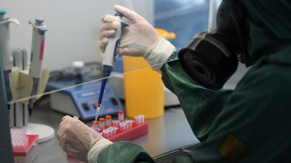 Сотрудник в костюме биозащиты за работой в вирусологической лаборатории, где производится анализ на новую коронавирусную инфекцию