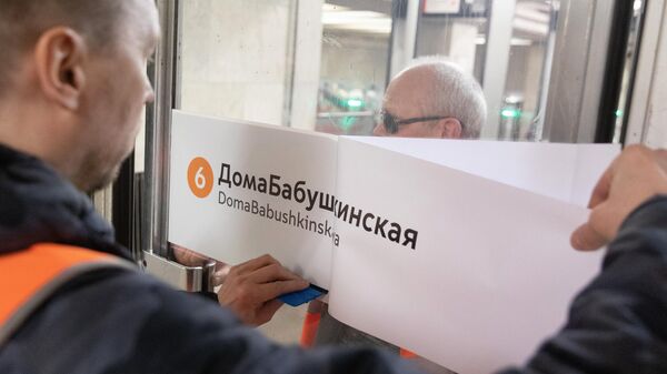 Сотрудник метрополитена приклеивает на двери стикер ДомаБабушкинская