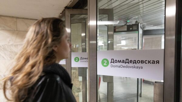 Пассажир у входа на станцию метро со стикером на дверях ДомаДедовская