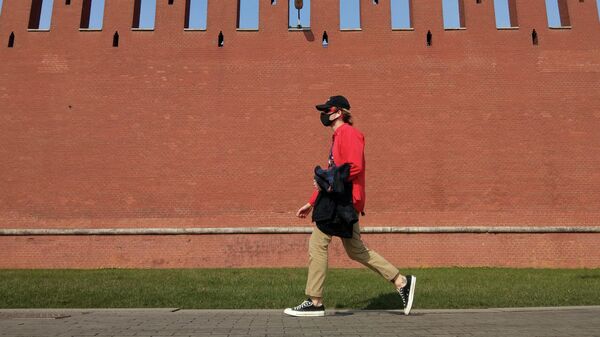 Молодой человек в медицинской маске идет возле Кремлевской стены в Москве