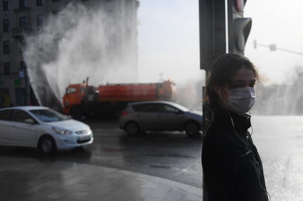 Девушка в медицинской маске на пешеходном переходе на Тверской улице в Москве