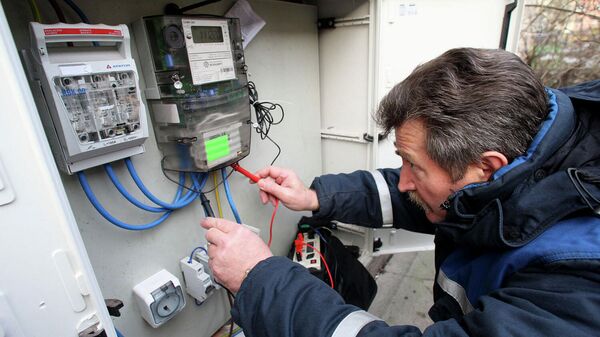 Электрик осуществляет проверку общедомового прибора учета потребления электроэнергии в одном из жилых домов