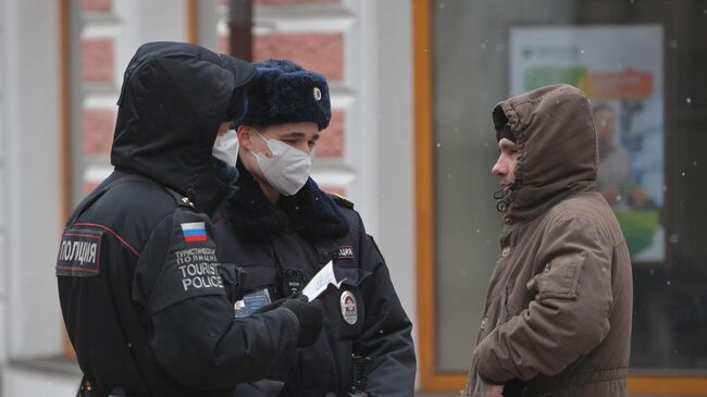 Сотрудники полиции проверяют документы прохожего на улице в Москве