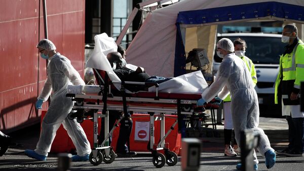 Медработники перевозят пациента на носилках в больнице Анри Мондора в Кретее, недалеко от Парижа