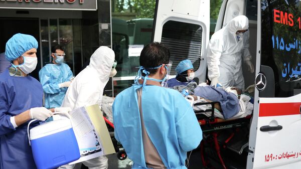 Врачи скорой медицинской помощи перевозят пациента с коронавирусом в больницу в Тегеране