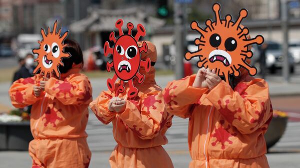 Активисты в масках с изображением коронавируса во время акции в Сеуле, Южная Корея
