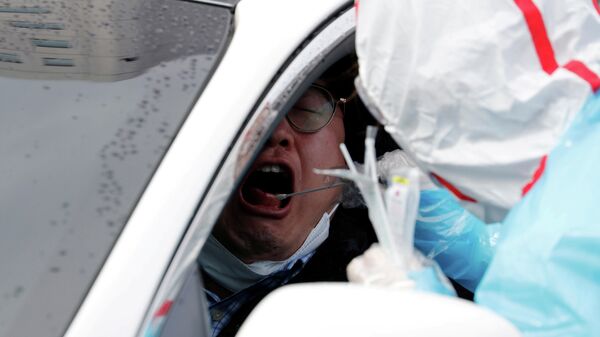 Медицинский работник делает тест на коронавирус водителю в центре Drive-Thru в Южной Корее
