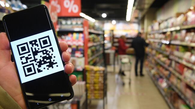 Человек держит смартфон с изображением QR-кода